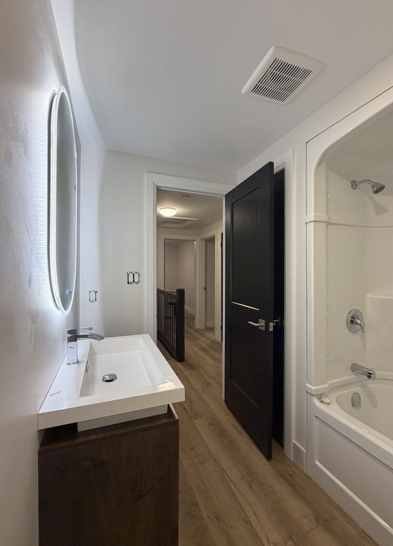 Modern bathroom with crisp white walls and a black painted door and trim by Paint Pure
