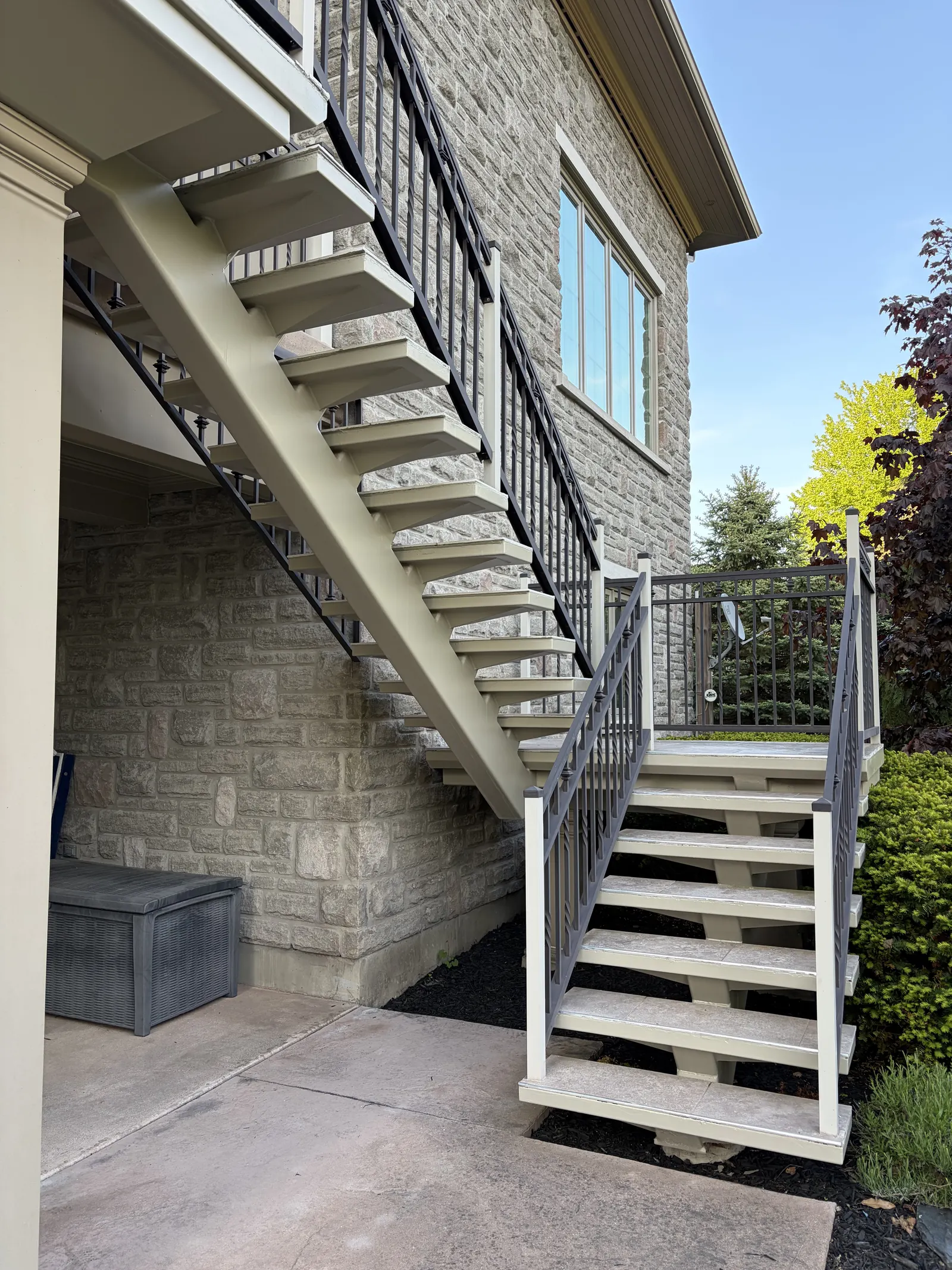 Exterior deck staircase after repainting with clean stringers and black railings by Paint Pure