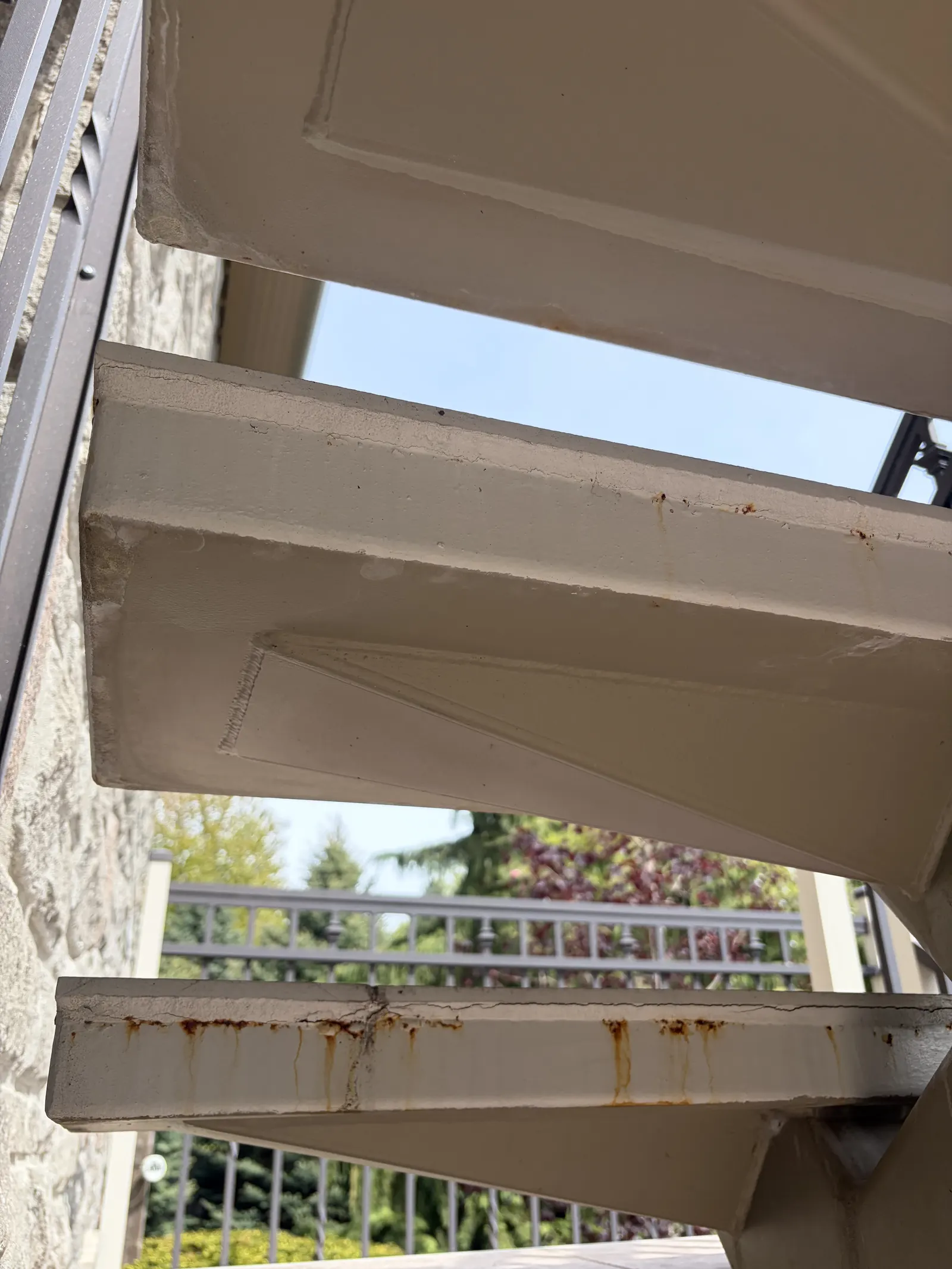 Rust streaks and peeling paint on a deck staircase before restoration by Paint Pure