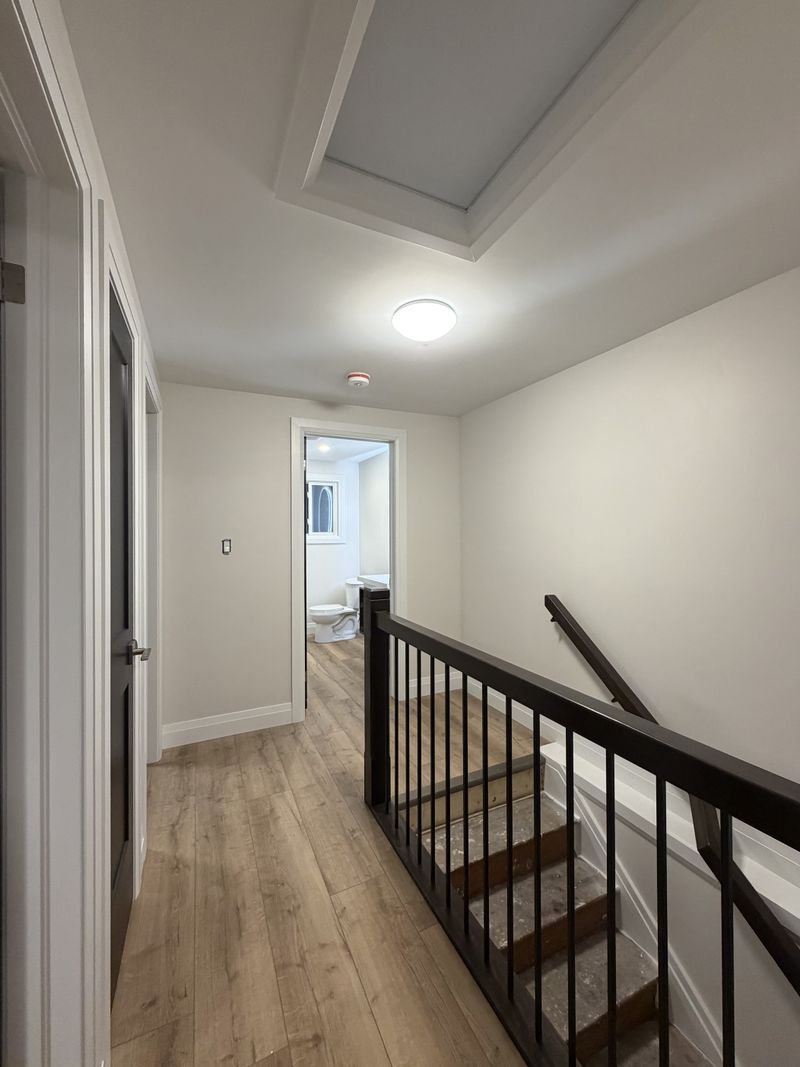Freshly painted upstairs hallway with a tray ceiling and black stair railing by Paint Pure